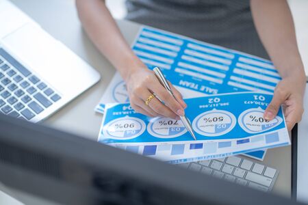Asian business woman reviewing data in financial charts and graphs. Accountingの写真素材