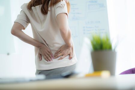 Asian woman with back pain in officeの写真素材