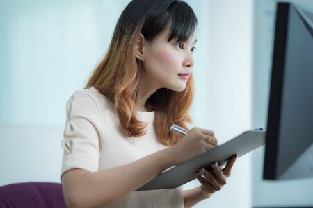 Asian businesswoman laughing with joy at workplace, gladly looking at laptop screen, feeling excited about online win, watching funny video on computer, enjoying positive good news in internetの写真素材