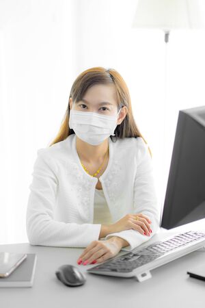 Asian woman using the medical face mask in officeの写真素材