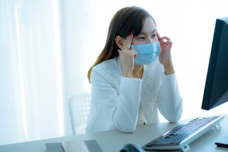 Asian woman using the medical face mask in officeの写真素材