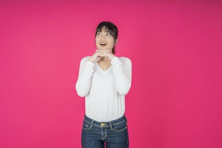 Do not miss. Young asian woman shouting. Shout. Crying emotional  woman screaming on pink studio background. Female half-length portrait. Human emotions, facial expression concept. Trendyの写真素材