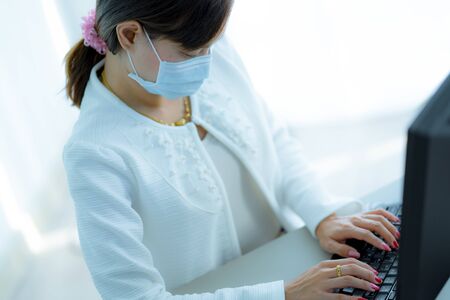 Asian woman using the medical face mask in officeの写真素材