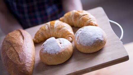 Woman Hands Hold Wooden Tray Present Fresh Baked Bakeryの写真素材
