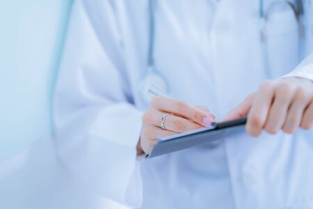 Close-up view of female doctor hands filling patient registration form. Healthcare and medical conceptの写真素材