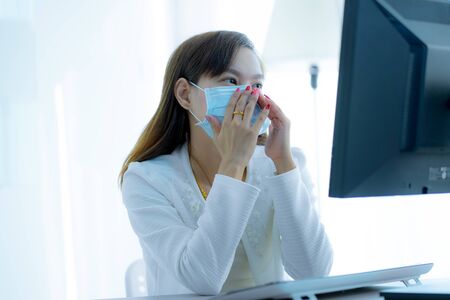 Asian woman using the medical face mask in officeの写真素材