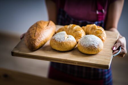 Woman Hands Hold Wooden Tray Present Fresh Baked Bakeryの写真素材