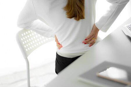 Asian woman with back pain in office