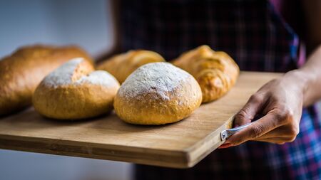 Woman Hands Hold Wooden Tray Present Fresh Baked Bakeryの写真素材