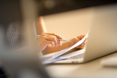 Asian business woman reviewing data in financial charts and graphs. Accounting