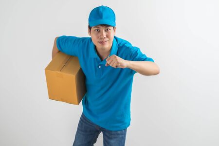Young smiling logistic delivery man in blue uniform holding the box on white background. Asian peopleの写真素材