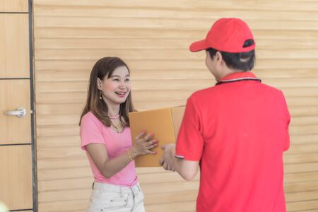 Asian woman receiving a package at home from a delivery guyの写真素材