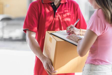 Asian woman receiving a package at home from a delivery guy