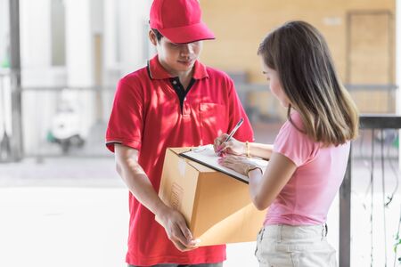Asian woman receiving a package at home from a delivery guyの写真素材