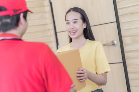 Asian woman receiving a package at home from a delivery guyの写真素材