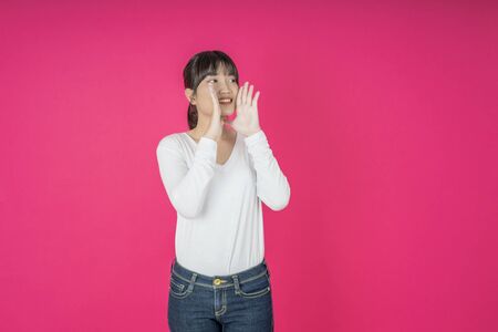 Do not miss. Young asian woman shouting. Shout. Crying emotional  woman screaming on pink studio background. Female half-length portrait. Human emotions, facial expression concept. Trendyの写真素材