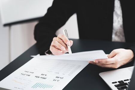 Asian business woman reviewing data in financial charts and graphs. Accounting conceptの写真素材