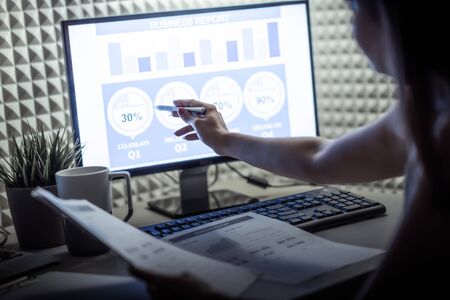 Asian business woman reviewing data in financial charts and graphs. Accounting