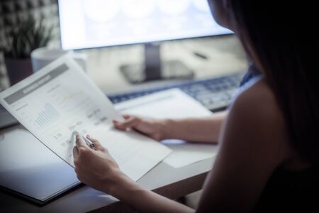 Asian business woman reviewing data in financial charts and graphs. Accountingの写真素材