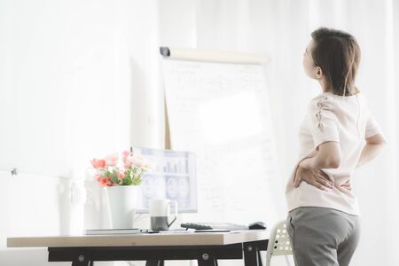Business woman with back pain in office. Asian people. Work at home conceptの写真素材