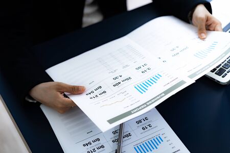 Asian business woman reviewing data in financial charts and graphs. Accounting conceptの写真素材