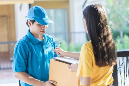 Asian woman receiving a package at home from a delivery guy