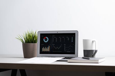 Laptop with  graph chart report screen on work table. Home office or work space. Strategy analysis...