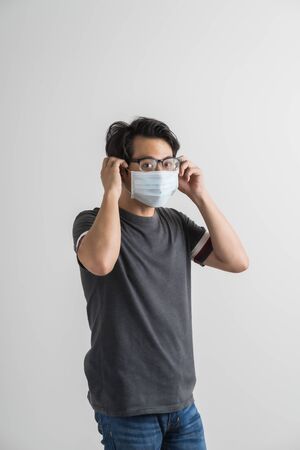 Portrait of young man with medicine health care mask against white gray background. Asian peopleの写真素材