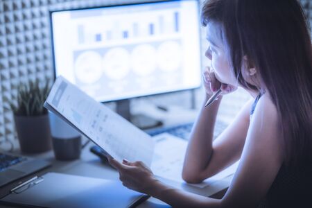 Asian business woman reviewing data in financial charts and graphs. Accountingの写真素材