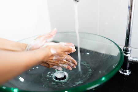 Washing hands with soap under the faucet with waterの写真素材