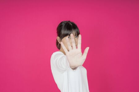 young asian woman protects herself by exposing her hand in front of herの写真素材