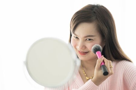 Asian woman looking to mirror doing makeup at homeの写真素材