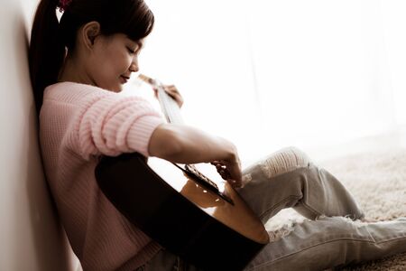 A beautiful asian woman playing acoustic guitarの写真素材