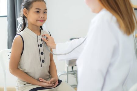 Asian doctor examining a little girl by stethoscopeの写真素材