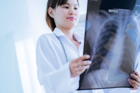 Asia Woman Doctor Looking at X-Ray Radiography in patient's Roomの写真素材