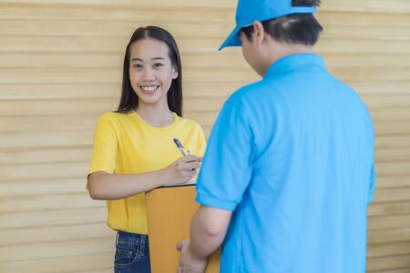 Asian woman receiving a package at home from a delivery guyの写真素材