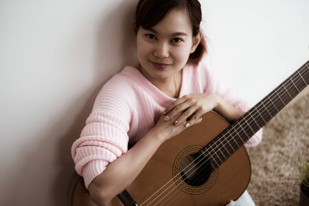 A beautiful asian woman playing acoustic guitarの写真素材