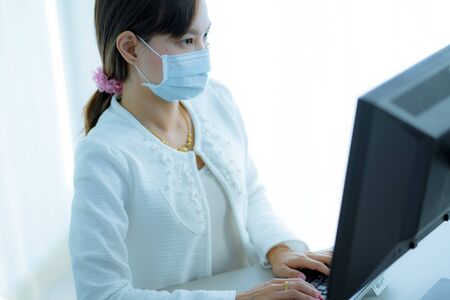 Asian woman using the medical face mask in officeの写真素材