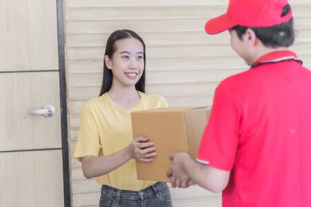 Asian woman receiving a package at home from a delivery guyの写真素材