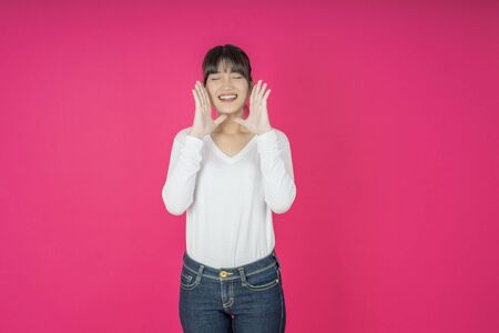 Do not miss. Young asian woman shouting. Shout. Crying emotional  woman screaming on pink studio background. Female half-length portrait. Human emotions, facial expression concept. Trendyの写真素材