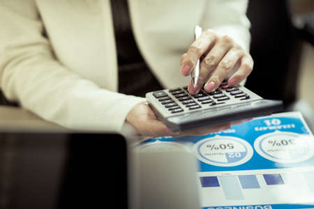 Asian business woman reviewing data in financial charts and graphs. Accountingの写真素材
