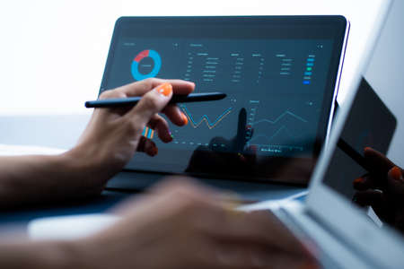 Asian business woman reviewing data in financial charts and graphs with tablet. Accountingの写真素材