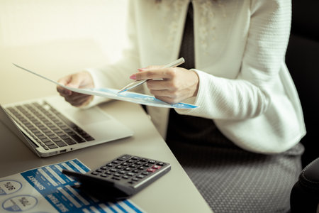 Asian business woman reviewing data in financial charts and graphs. Accounting