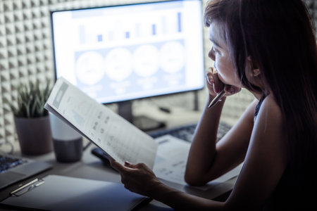 Asian business woman reviewing data in financial charts and graphs. Accountingの写真素材