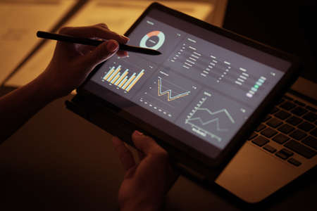 Asian business woman reviewing data in financial charts and graphs with tablet. Accountingの写真素材