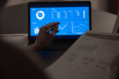 Asian business woman reviewing data in financial charts and graphs with tablet. Accounting