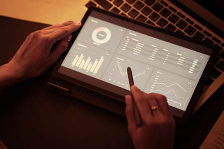 Asian business woman reviewing data in financial charts and graphs with tablet. Accountingの写真素材