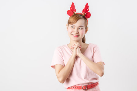 Asian woman is wearing christmas reindeer antlers over grey background.の写真素材