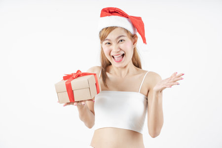Asian woman is wearing christmas reindeer antlers holding big giftbox in hands grey background.の写真素材