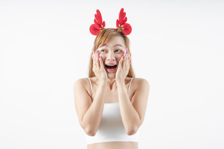 Asian woman is wearing christmas reindeer antlers over grey background.の写真素材